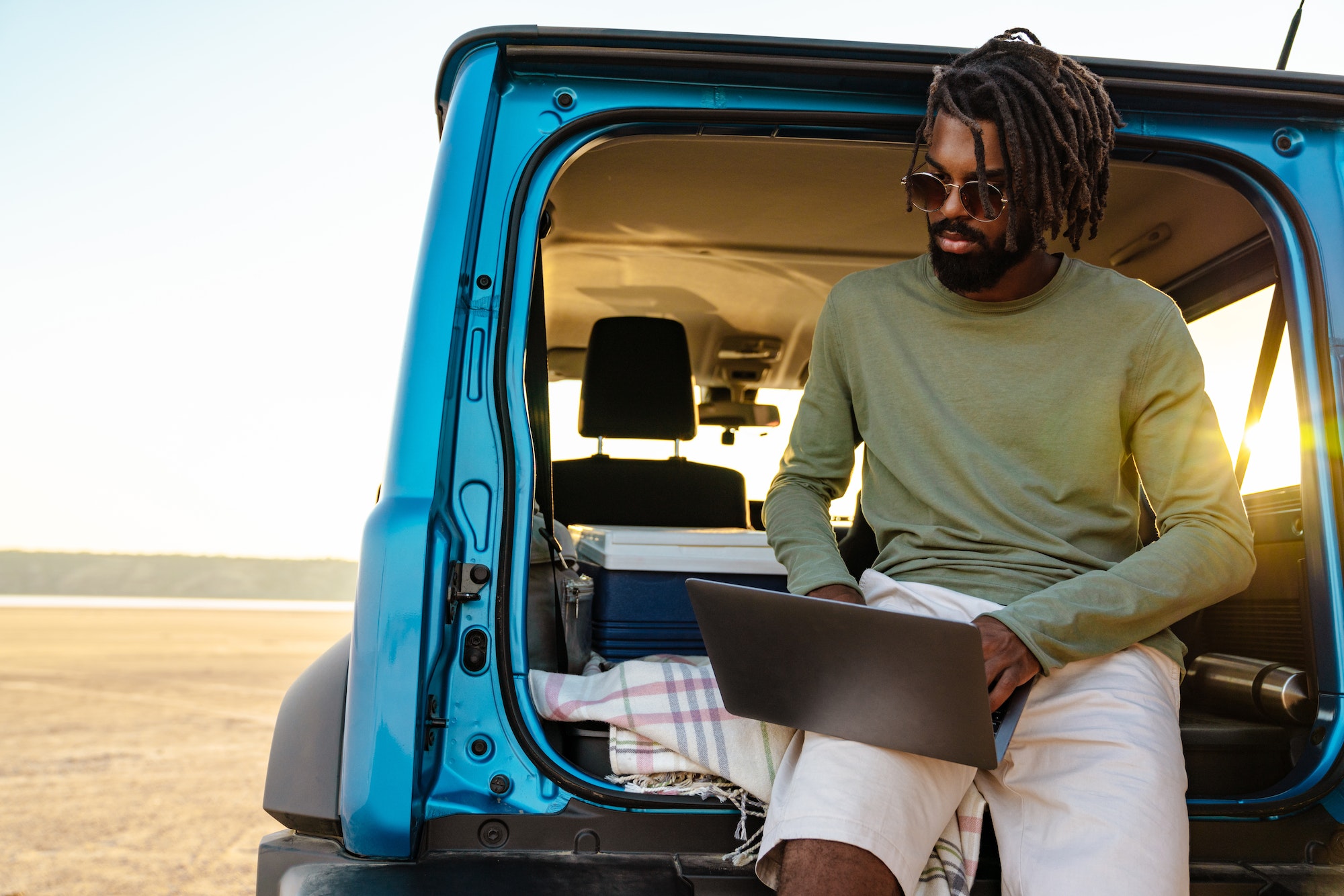 Os Melhores Destinos na África para Conhecer de Carro. Suzuki Jimny Jeep Renagade Image of african american man using laptop while travelling with car