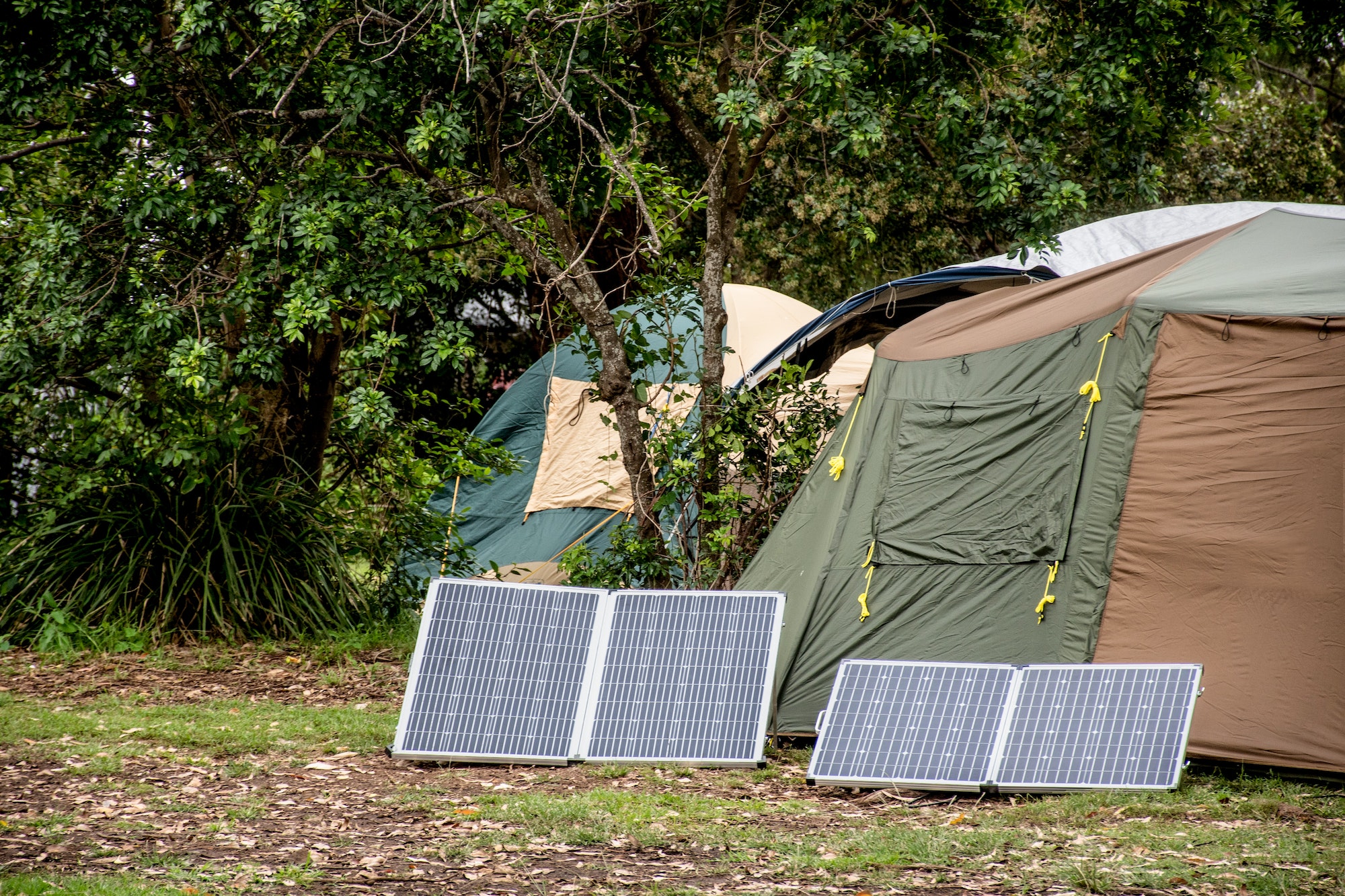 Energia Solar Portátil para Viagens, Camping with solar panels. Portable foldable solar panels near the tent.