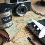 Vacation money saving in a glass with camera on map, Travel budget concept